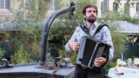 Pamhpile et son accordéon, jouant addossé à la rambarde d'un bateau au RDV de l'erdre