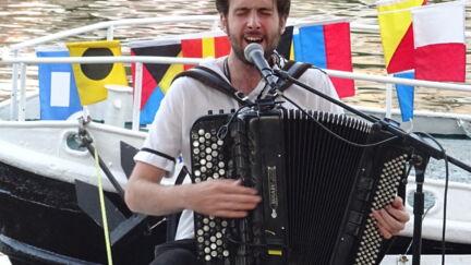 Pamphile joue de l'accordéon et chante sur un bateau de l'ABPN