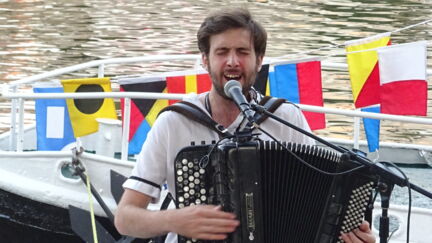 Pamphile joue de l'accordéon et chante sur un bateau de l'ABPN