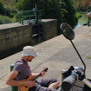 Pamphile joue du ukulele assis par terre